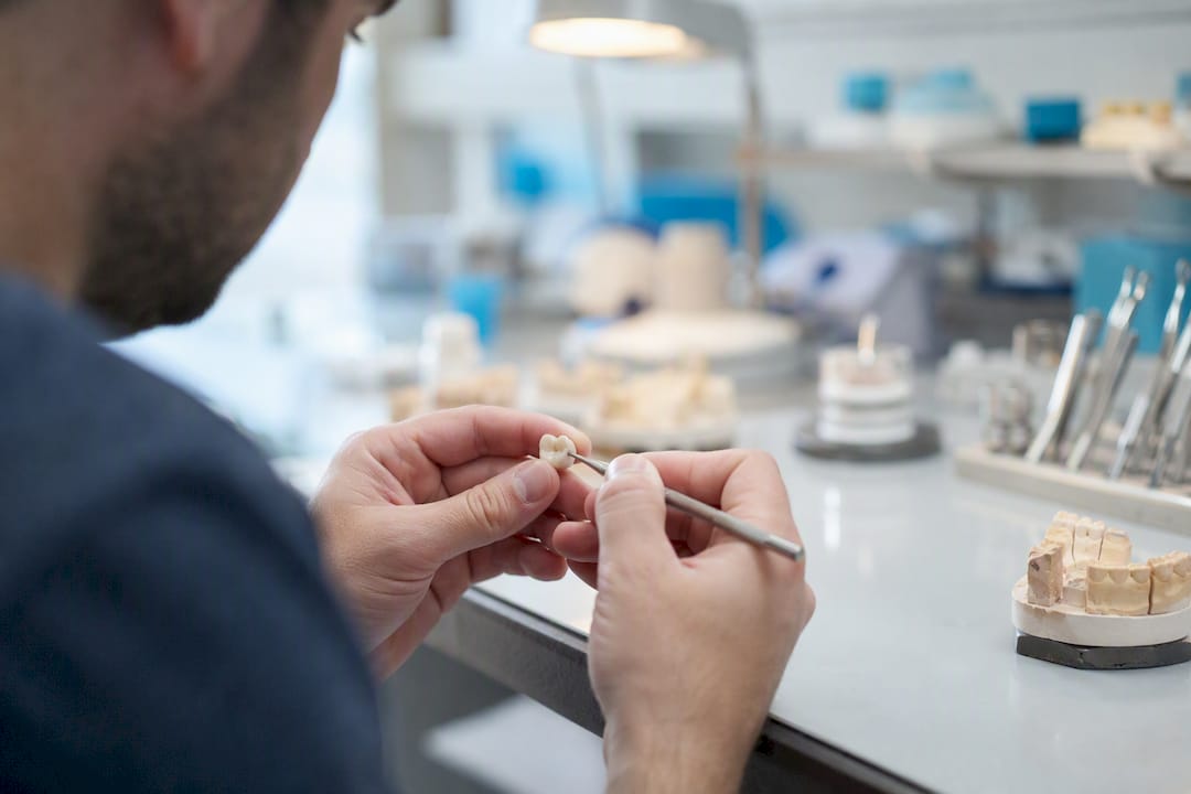 Hands working on a dental crown in a clinic