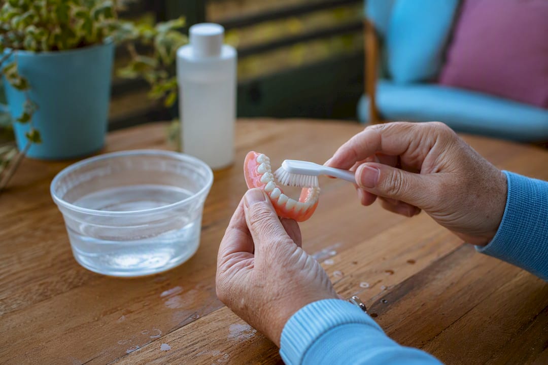 Hands cleaning removable overdenture with denture brush